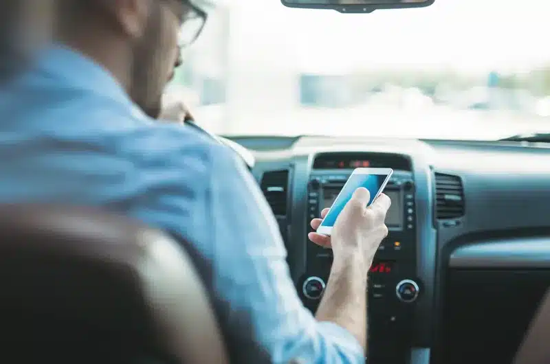 guy sitting in car looking at phone