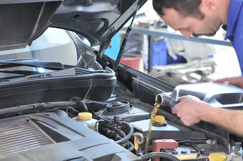 mechanic pouring oil into vehicle