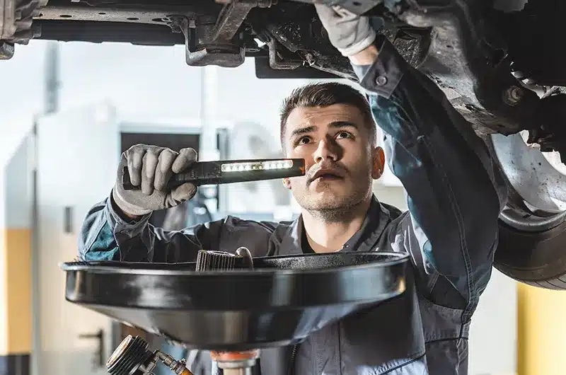 Service Tech Looking At Oil With Light service tech looking at oil with light
