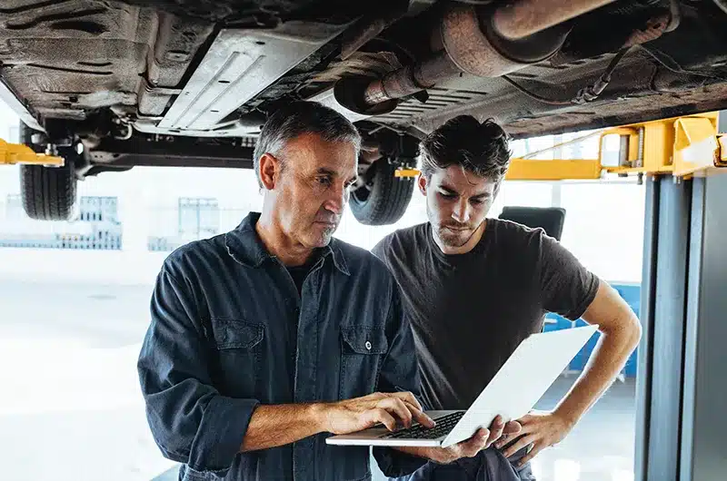 two car mechanics looking at laptop