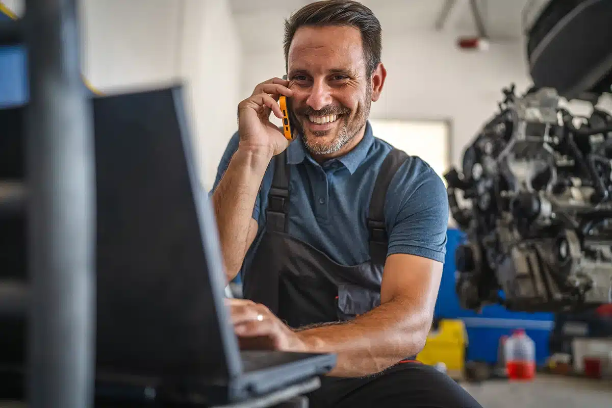 Mechanic On Phone Looking At Laptop mechanic on phone looking at laptop